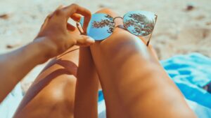 Gambe di donna abbronzate con occhiali da sole appoggiati sul ginocchio