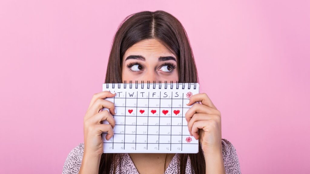 Ragazza con dolori mestruali tiene in mano un calendario su cui sono segnati i giorni del ciclo