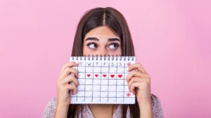 Ragazza con dolori mestruali tiene in mano un calendario su cui sono segnati i giorni del ciclo