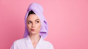 Pulizia del viso: ragazza con turbante in microfibra viola che si asciuga i capelli